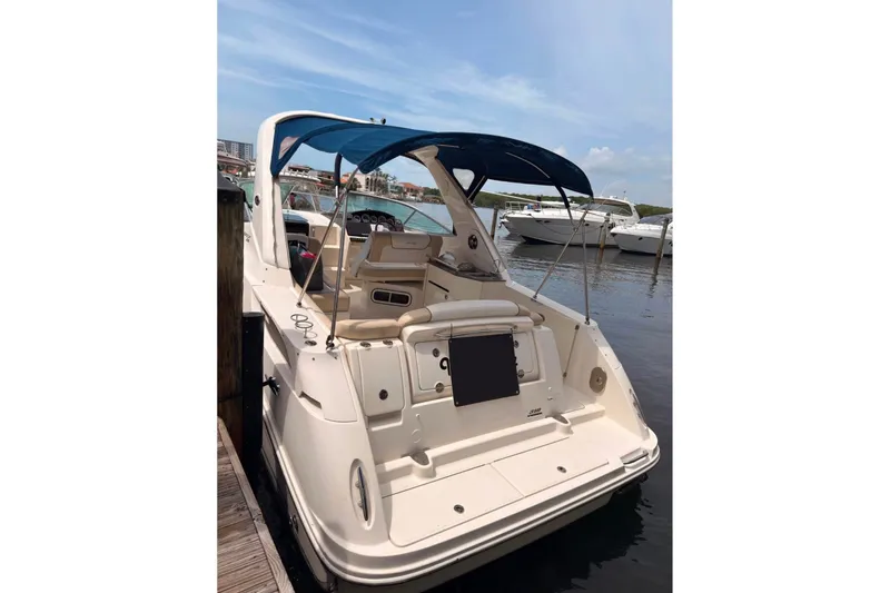 Slide: The Image of 2013 Sea Ray Sundancer 310 docked, featuring a blue canopy and spacious deck. - 3