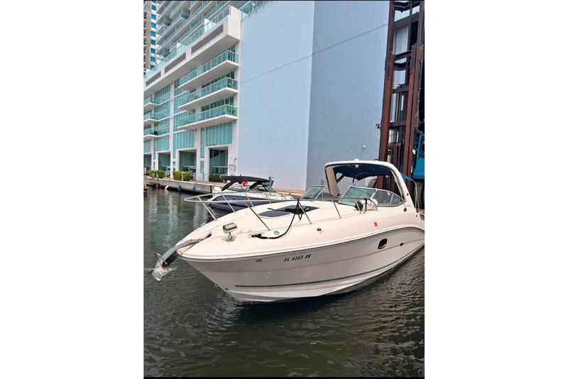 The Image of 2013 Sea Ray Sundancer 310 yacht docked near modern waterfront buildings. - 1