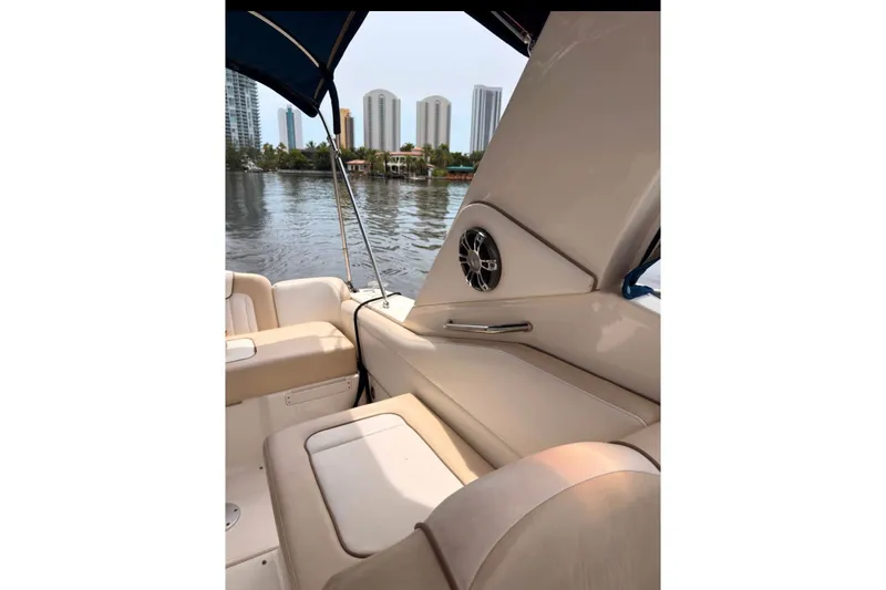 Slide: The Image of 2013 Sea Ray Sundancer 310 interior with beige seating, overlooking waterfront cityscape. - 4