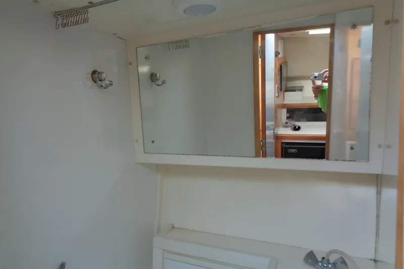 Slide: The Image of Interior of 1994 Bertram 30 Moppie boat, featuring a bathroom mirror and sink area. - 39