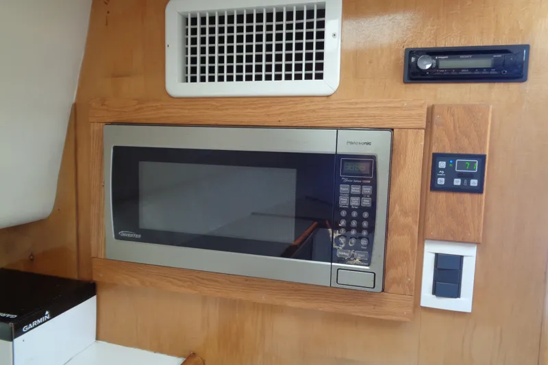 Slide: The Image of Built-in microwave in 1994 Bertram 30 Moppie boat interior, featuring wooden paneling. - 36
