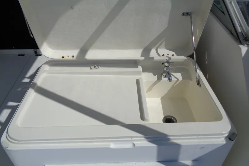 Slide: The Image of Open sink compartment on 1994 Bertram 30 Moppie boat, featuring faucet and drain. - 18
