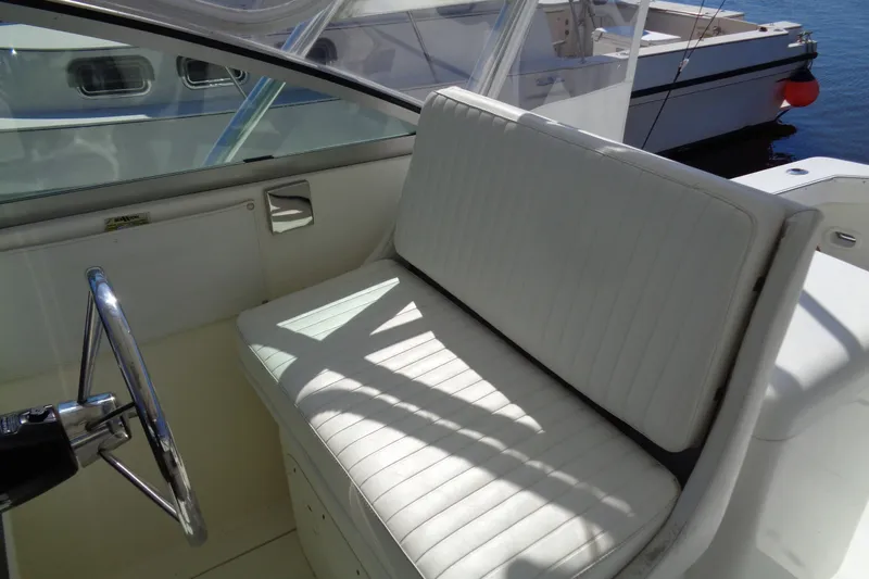 Slide: The Image of Interior of a 1994 Bertram 30 Moppie boat with white seating and steering wheel. - 17