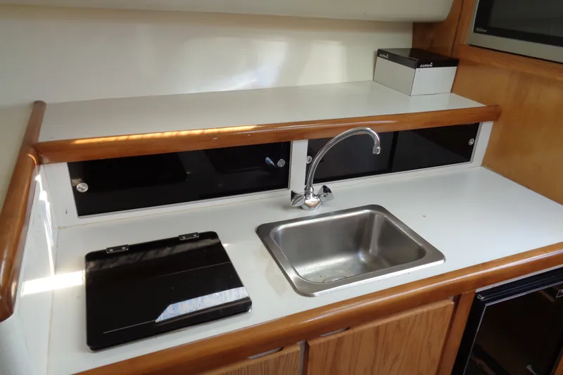 Slide: The Image of 1994 Bertram 30 Moppie yacht kitchenette with sink, stove, and storage cabinets. - 35