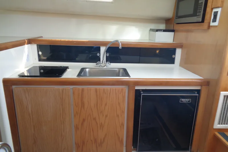 Slide: The Image of 1994 Bertram 30 Moppie boat kitchen with sink, stove, microwave, and fridge. - 32