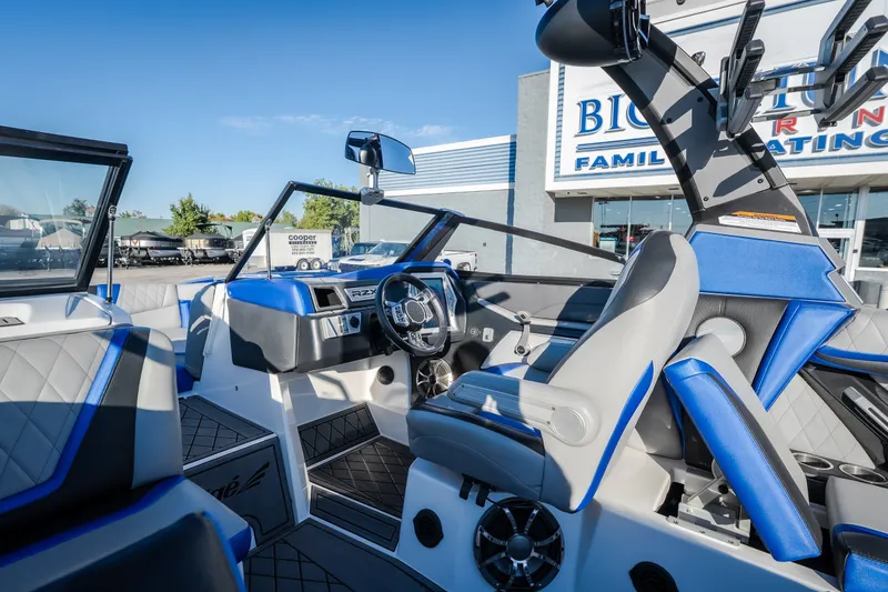 Slide: The Image of 2018 Tigé RZX3 boat interior with blue and gray seating, steering wheel, and dashboard. - 54