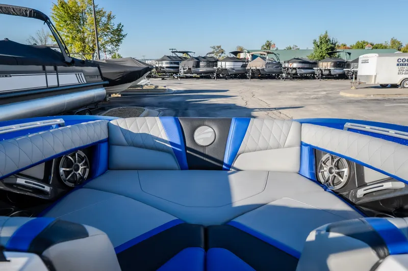 Slide: The Image of 2018 Tigé RZX3 boat interior with blue and gray seating, parked in a marina. - 11