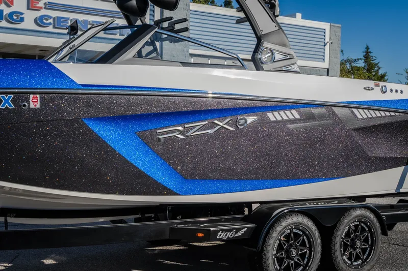 Slide: The Image of 2018 Tigé RZX3 boat with blue and black glitter finish on a trailer. - 36
