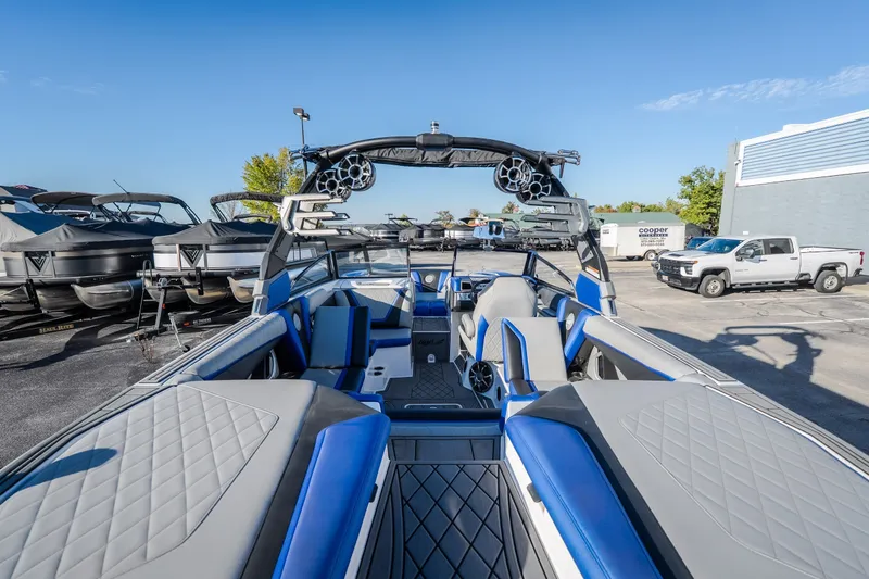 Slide: The Image of 2018 Tigé RZX3 boat interior with blue and gray seating, parked outdoors. - 21