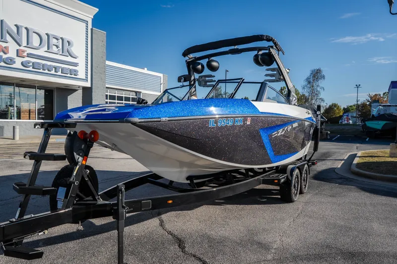 Slide: The Image of 2018 Tigé RZX3 boat on trailer at dealership, sunny day. - 2