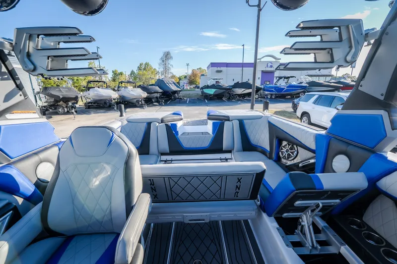 Slide: The Image of 2018 Tigé RZX3 boat interior with blue and gray seating, parked in a marina. - 41
