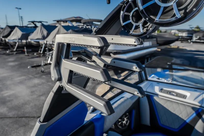 Slide: The Image of 2018 Tigé RZX3 boat with wakeboard racks and speakers, parked outdoors. - 23