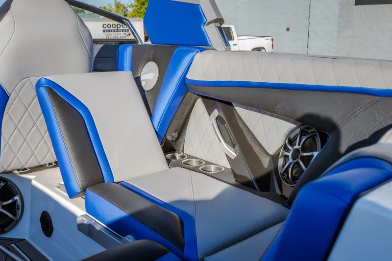 Slide: The Image of 2018 Tigé RZX3 boat interior with blue and gray seating, cup holders, and speaker system. - 7