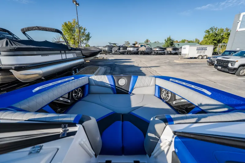 Slide: The Image of 2018 Tigé RZX3 boat interior with blue and gray seating, parked in a marina. - 9
