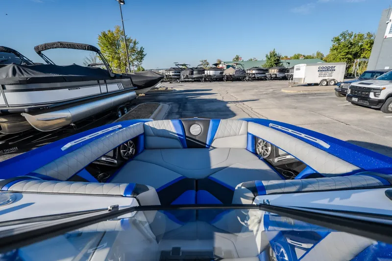 Slide: The Image of 2018 Tigé RZX3 boat interior with blue and gray seating at a marina. - 42
