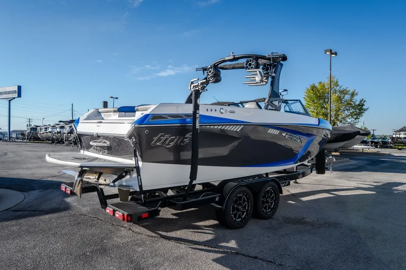 Slide: The Image of 2018 Tigé RZX3 boat on trailer in parking lot under clear blue sky. - 3