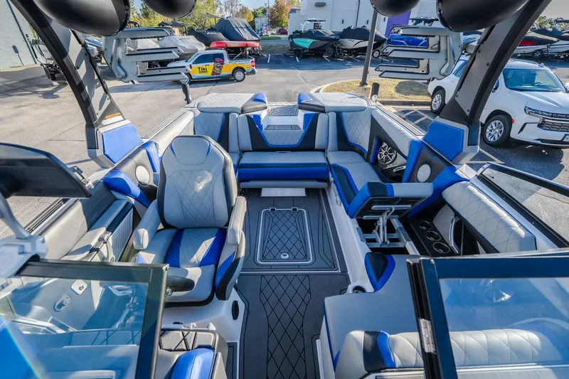 Slide: The Image of 2018 Tigé RZX3 boat interior with blue and gray seating, parked in a marina. - 14