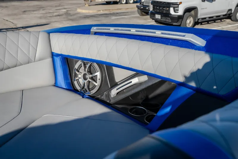 Slide: The Image of 2018 Tigé RZX3 boat interior with speaker and cup holders, featuring blue and gray upholstery. - 12