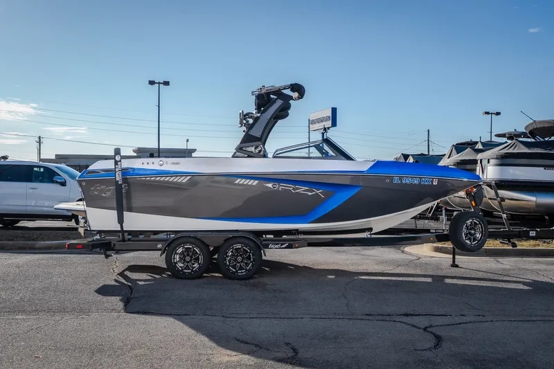 The Image of 2018 Tigé RZX3 boat on trailer, blue and gray design, parked outdoors. - 0