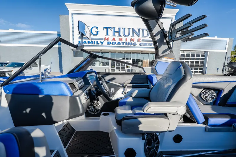 Slide: The Image of 2018 Tigé RZX3 boat interior with blue and gray seating at a marine center. - 18