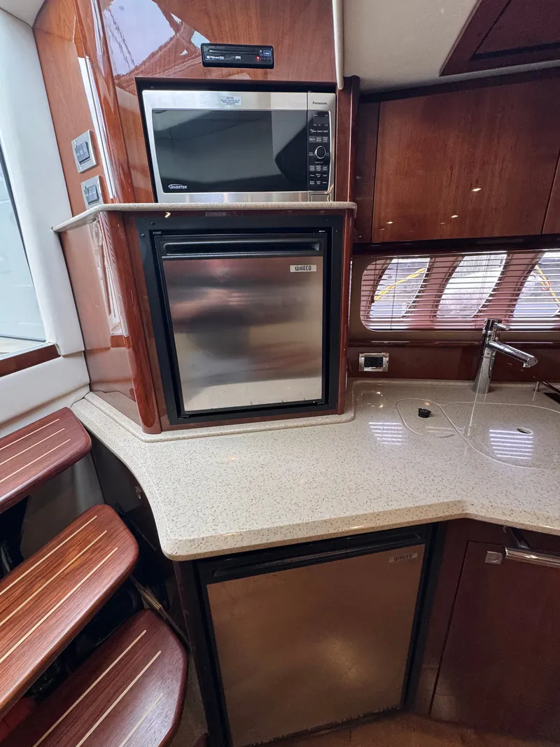 Slide: The Image of The 2010 Sea Ray 390 Sundancer's galley features a microwave and a refrigerator. - 27