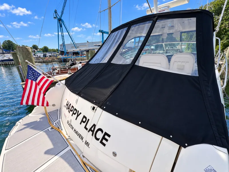 Slide: The Image of 2010 Sea Ray 390 Sundancer with black canopy and American flag, docked in a marina. - 18