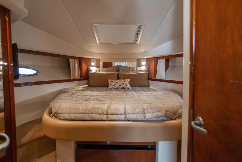 Slide: The Image of Cabin of the 2010 Sea Ray 390 Sundancer featuring a large bed and wood accents. - 32