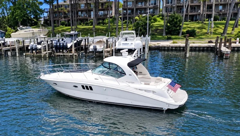 Slide: The Image of A white 2010 Sea Ray 390 Sundancer boat on calm water, with an American flag at the stern. - 1