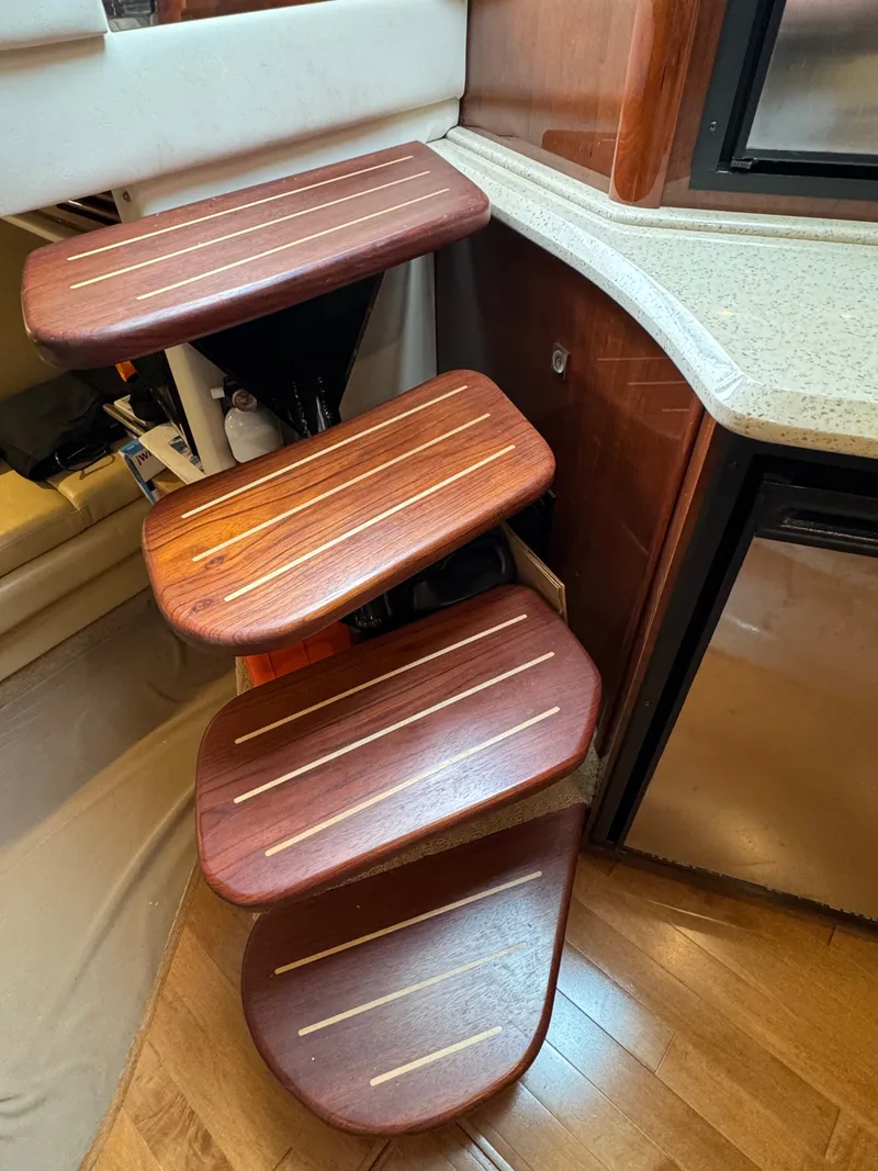 Slide: The Image of Wooden staircase with four steps in a boat cabin, surrounded by cabinets and carpeting. - 29
