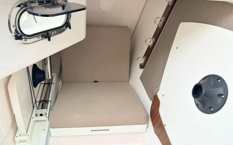 Slide: The Image of Interior of a Pursuit DC 325 Dual Console with cushioned seating and a porthole. - 18