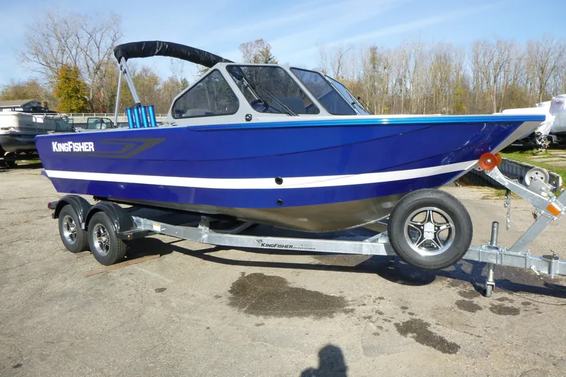 Slide: The Image of Blue 2027 KingFisher 2025 Escape boat on trailer, parked outdoors. - 1