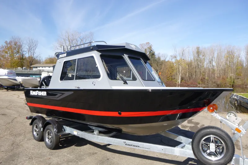 Slide: The Image of KingFisher 2025 Escape HT boat on trailer, black with red stripe, outdoors. - 1