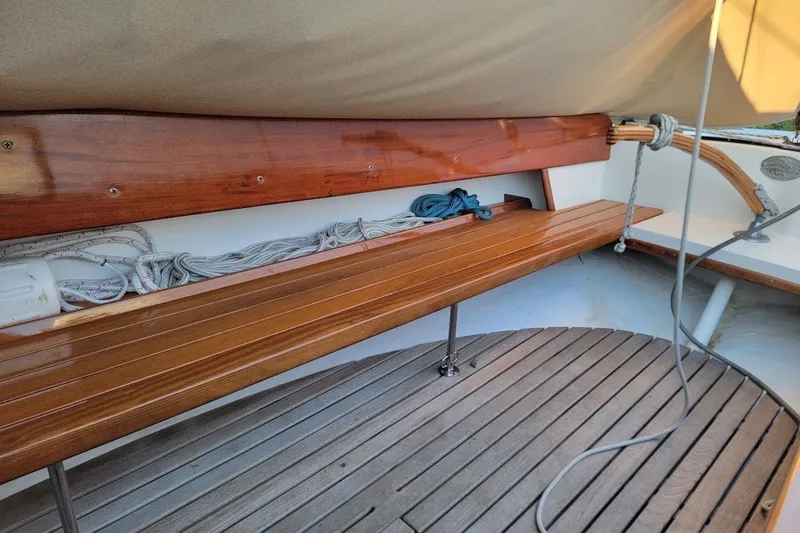 Slide: The Image of Wooden interior of 2006 Ensign 23 sailboat, featuring polished seating and coiled ropes. - 19