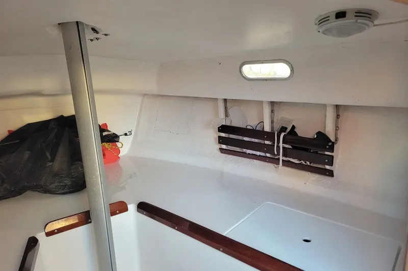 Slide: The Image of Interior of 2006 Ensign 23 sailboat, featuring storage and porthole. - 22