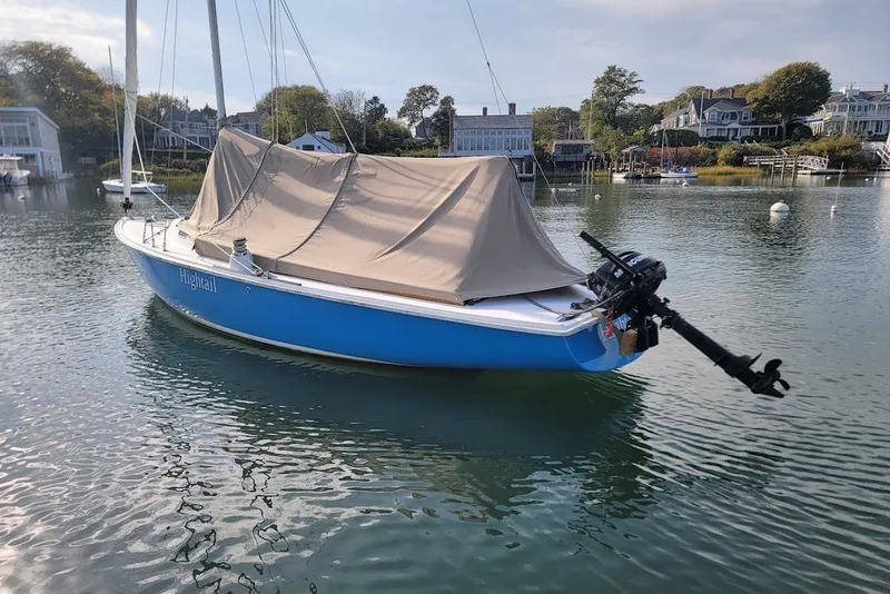 Slide: The Image of Blue 2006 Ensign 23 sailboat with cover, docked in a serene harbor setting. - 16