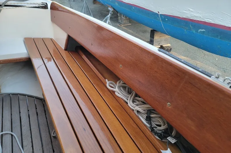 Slide: The Image of Wooden seating area on a 2006 Ensign 23 sailboat, featuring neatly coiled ropes. - 27