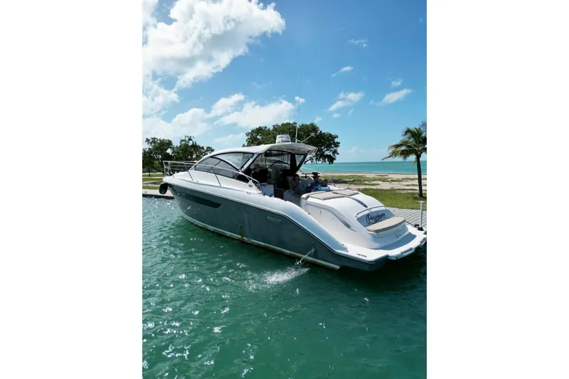 Slide: The Image of 2015 Pursuit SC 365i Sport Coupe docked by tropical shoreline under blue sky. - 21