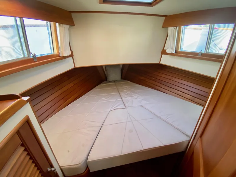 Slide: The Image of 1997 Grand Banks Classic boat cabin with wooden interior and cushioned bed. - 35