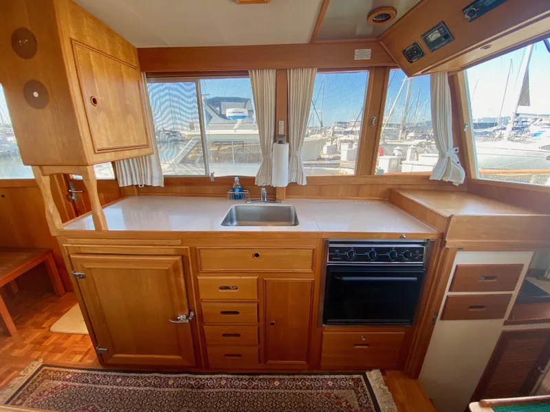 Slide: The Image of 1997 Grand Banks Classic yacht kitchen with wooden cabinetry, sink, and stove, overlooking marina. - 22