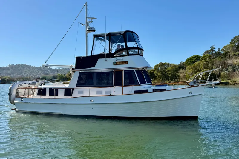 Slide: The Image of 1997 Grand Banks Classic yacht on calm water, surrounded by lush greenery. - 64