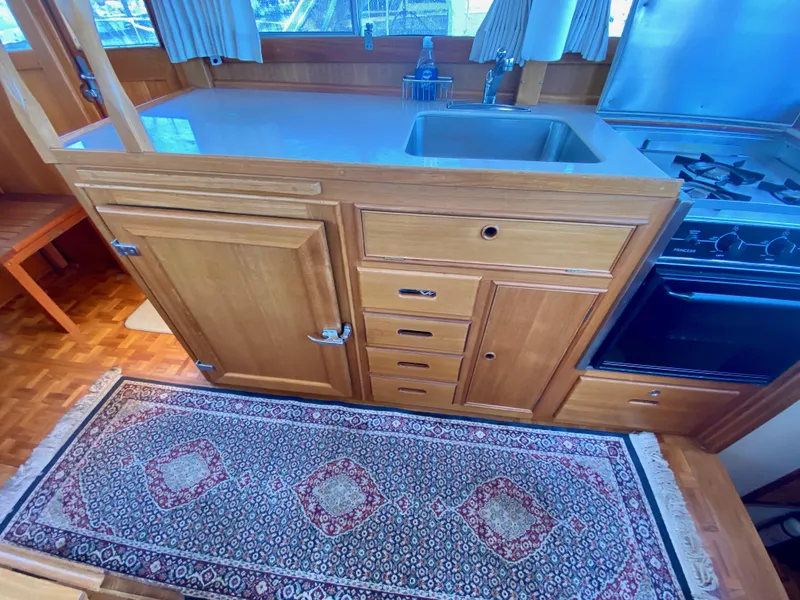 Slide: The Image of 1997 Grand Banks Classic yacht kitchen with wooden cabinets, stove, and patterned rug. - 23