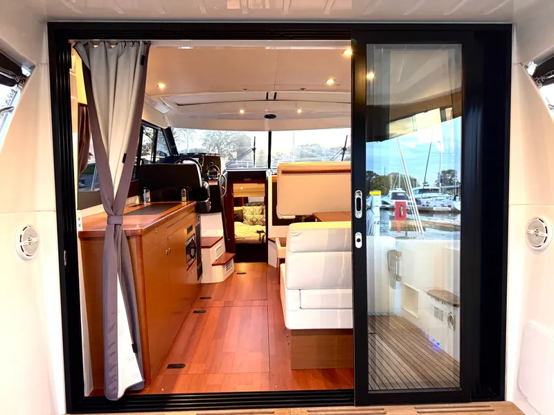 Slide: The Image of Interior view of a 2017 Jeanneau NC 11 with sleek wood finishes and white upholstery. - 16