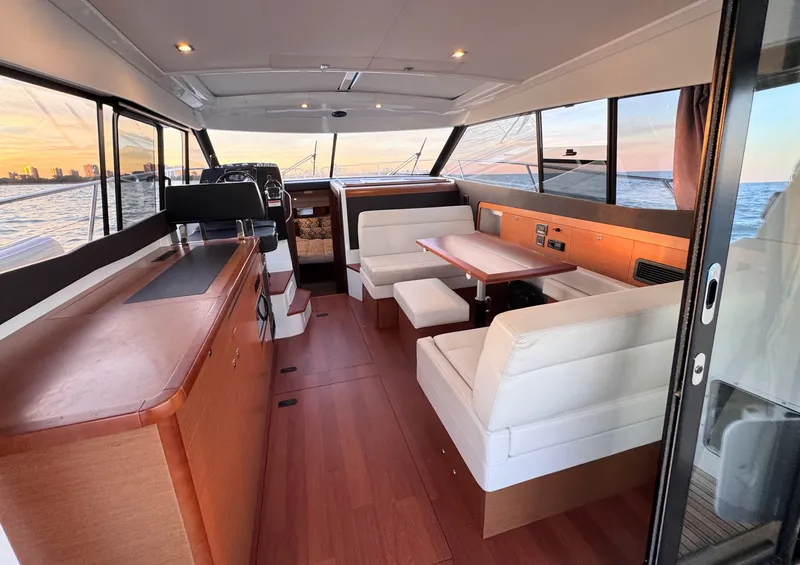 Slide: The Image of Interior of a 2017 Jeanneau NC 11 with sleek wood flooring and white upholstered seating. - 21