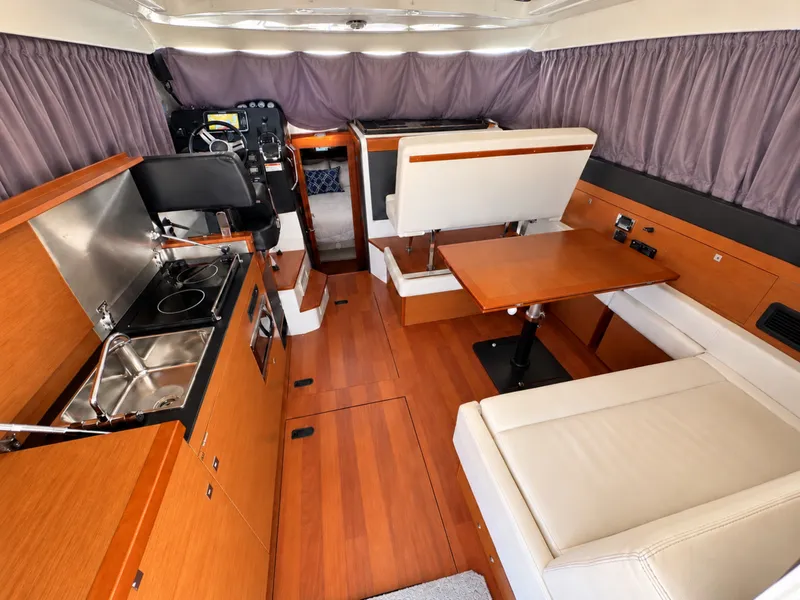 Slide: The Image of Interior of a 2017 Jeanneau NC 11 with wood flooring, kitchenette, and seating area. - 25