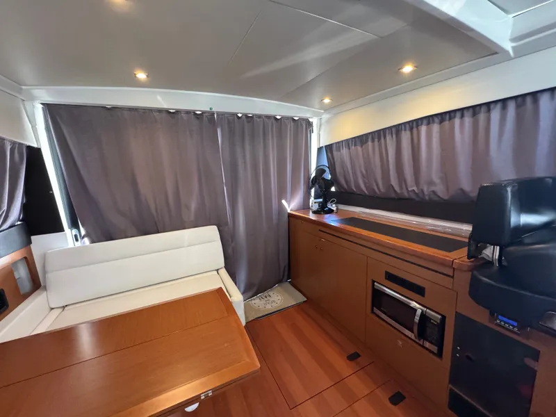 Slide: The Image of Interior of Jeanneau NC 11 with wooden table, white seating, and curtains. - 26