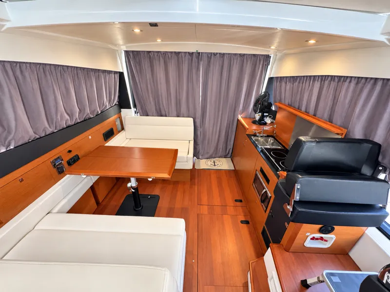 Slide: The Image of Interior of Jeanneau NC 11 with wood flooring, dining table, and kitchenette. - 24