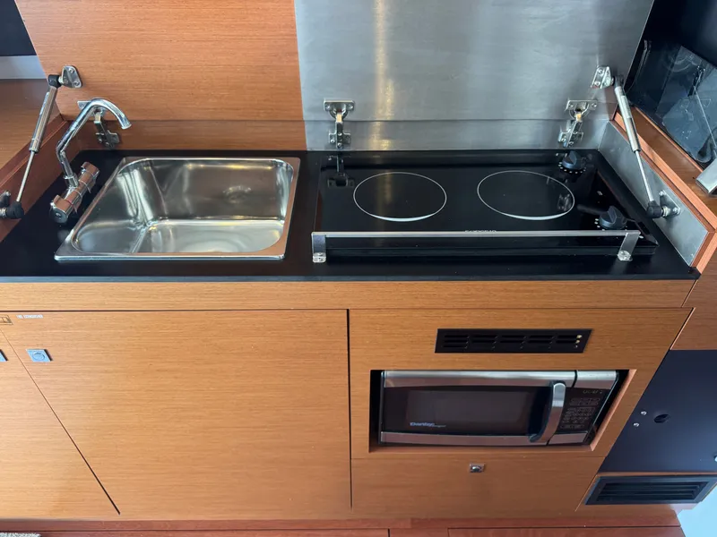Slide: The Image of Galley with sink, stove, and microwave in a Jeanneau NC 11 boat. - 19