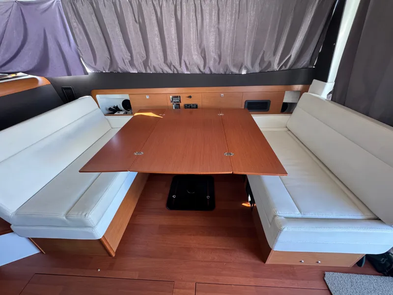 Slide: The Image of Interior of the Jeanneau NC 11 with a wooden table and white seating. - 32