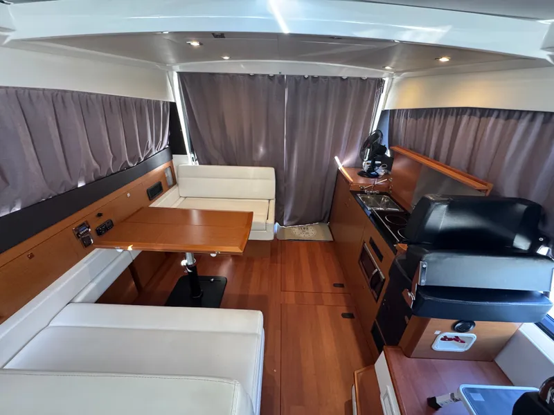 Slide: The Image of Interior of a 2017 Jeanneau NC 11 with wood flooring, dining table, and kitchenette. - 33