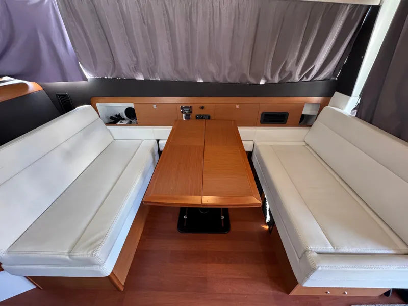 Slide: The Image of Interior of the 2017 Jeanneau NC 11 with a wooden table and white seating. - 31